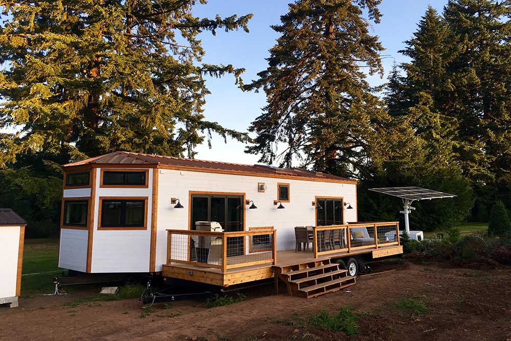 Exterior of a custom tiny home with a porch built by Tiny Heirloom