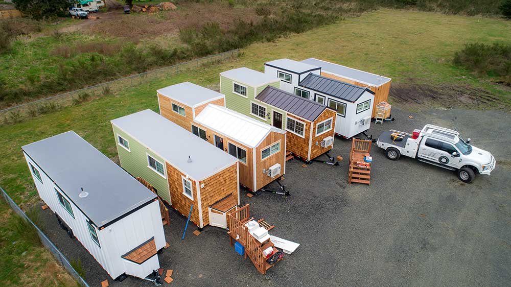 Overhead shot of five tiny homes and a truck, ready to be deployed as workforce housing for a coporation